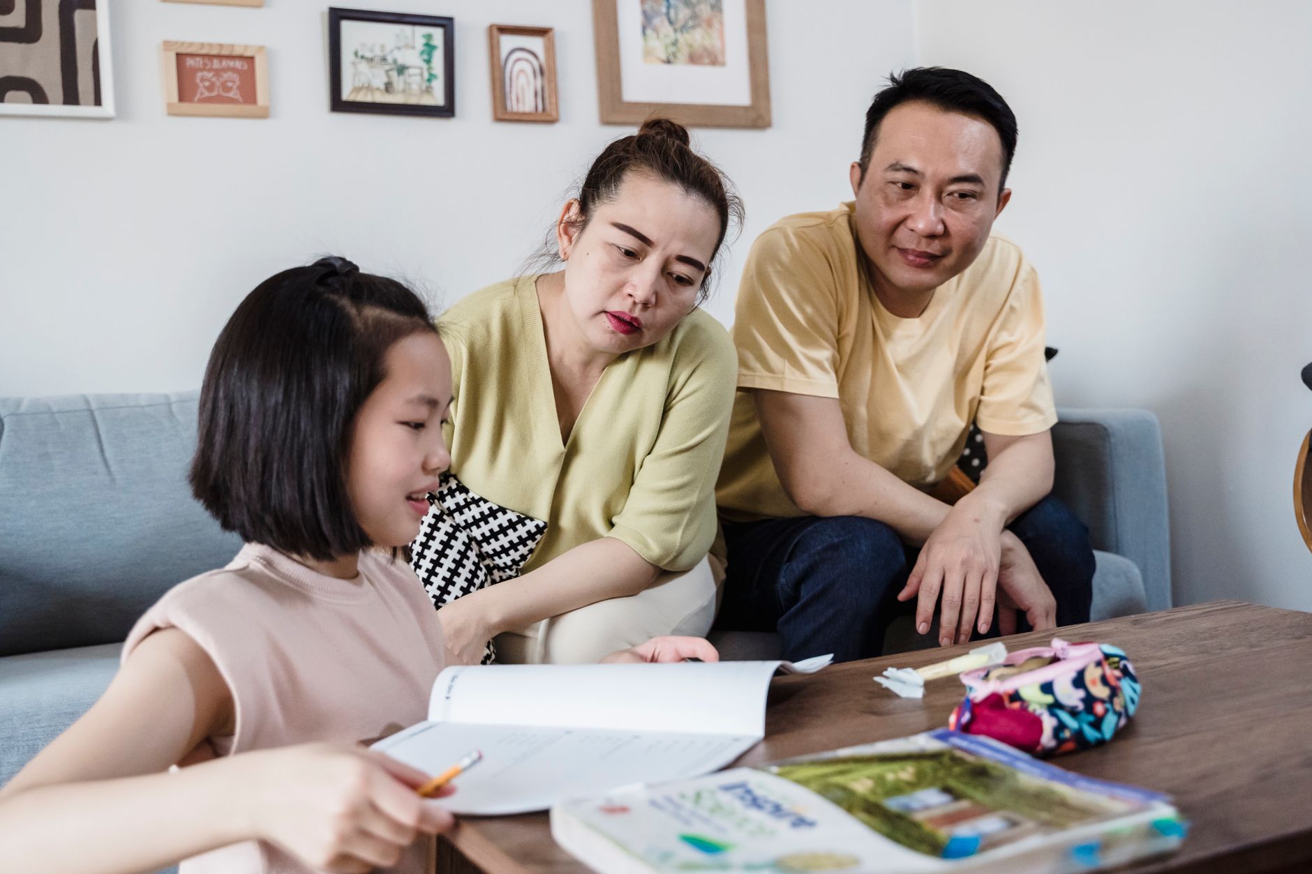 Parents watching their child complete homework at a table