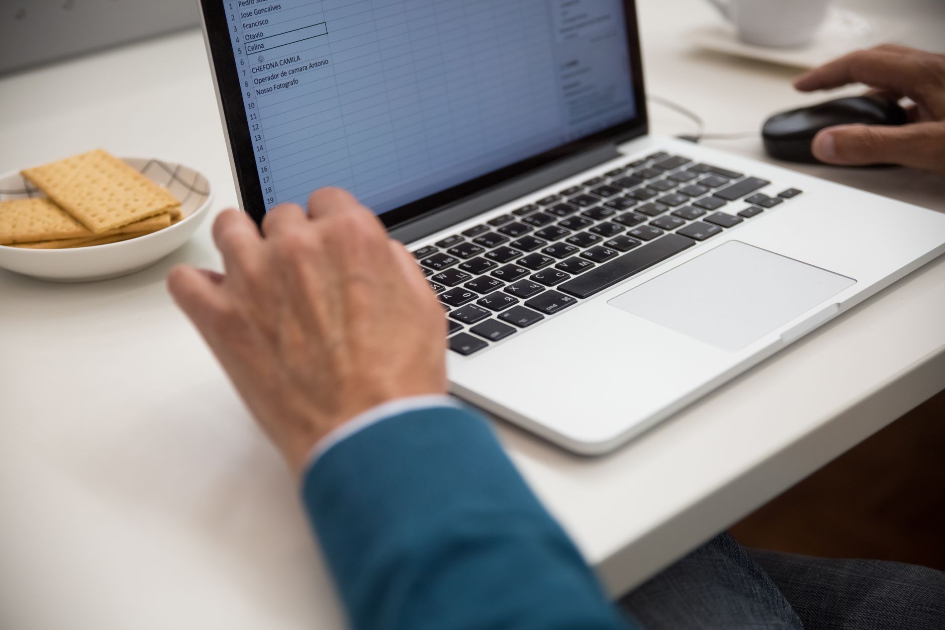 A person entering records into a spreadsheet on a laptop