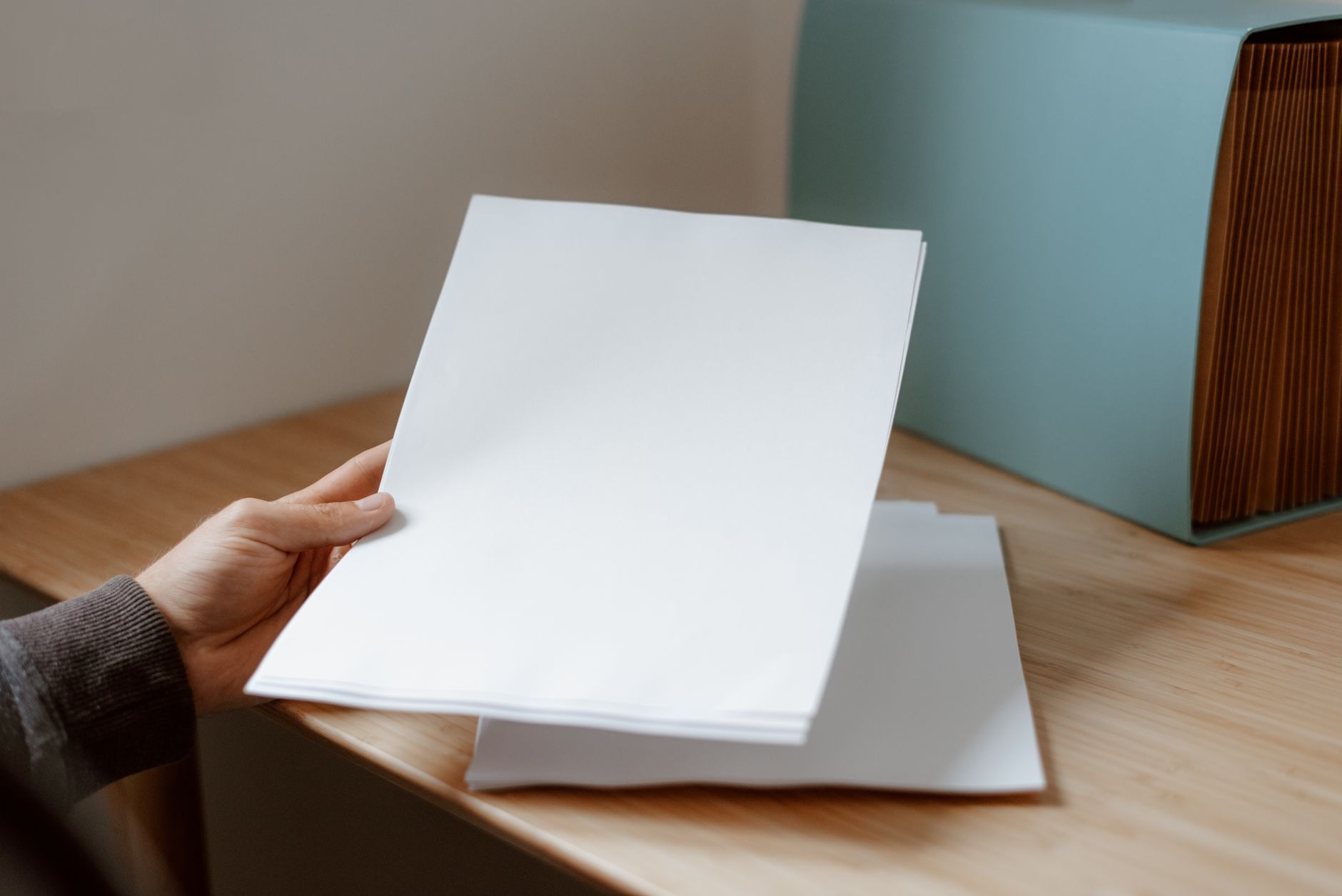 A person taking a printed sheet of paper from a stack of documents